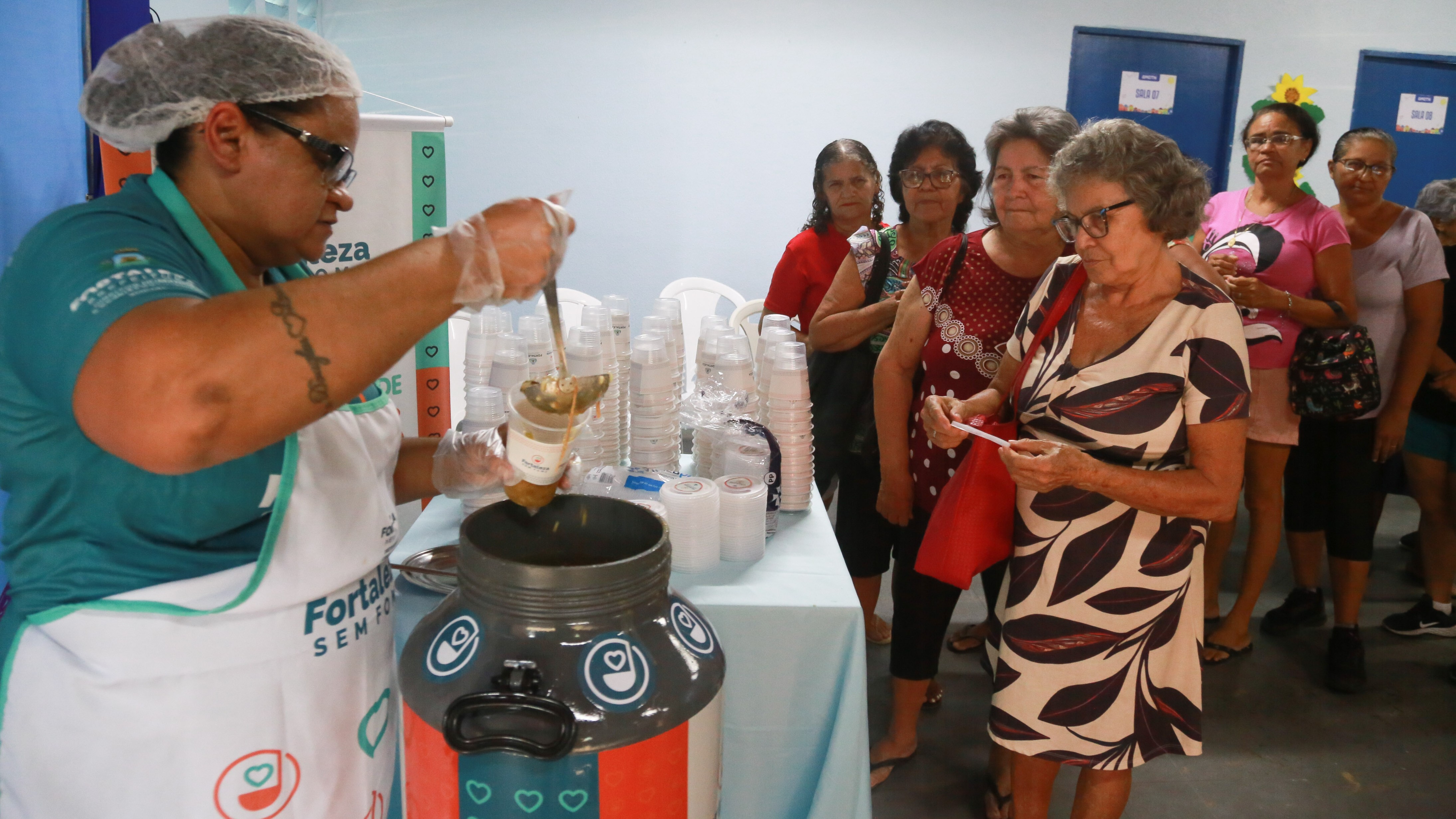 mulher serve sopa para uma senhora